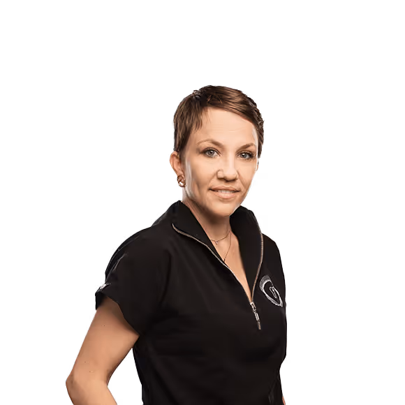 A woman with short brown hair, wearing a black zip-up shirt, with one hand on her hip.