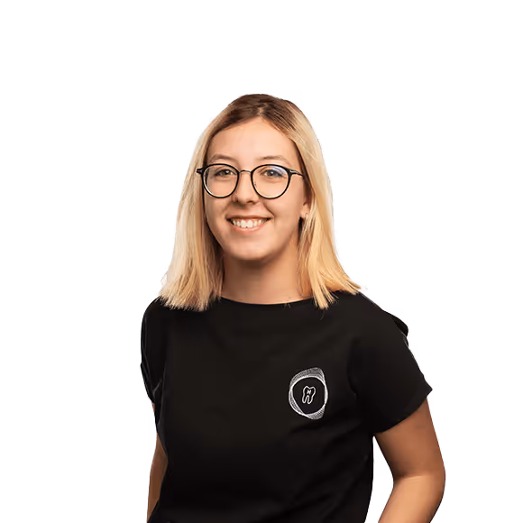 A smiling woman with shoulder-length blonde hair, wearing round glasses and a black shirt featuring a dental logo.