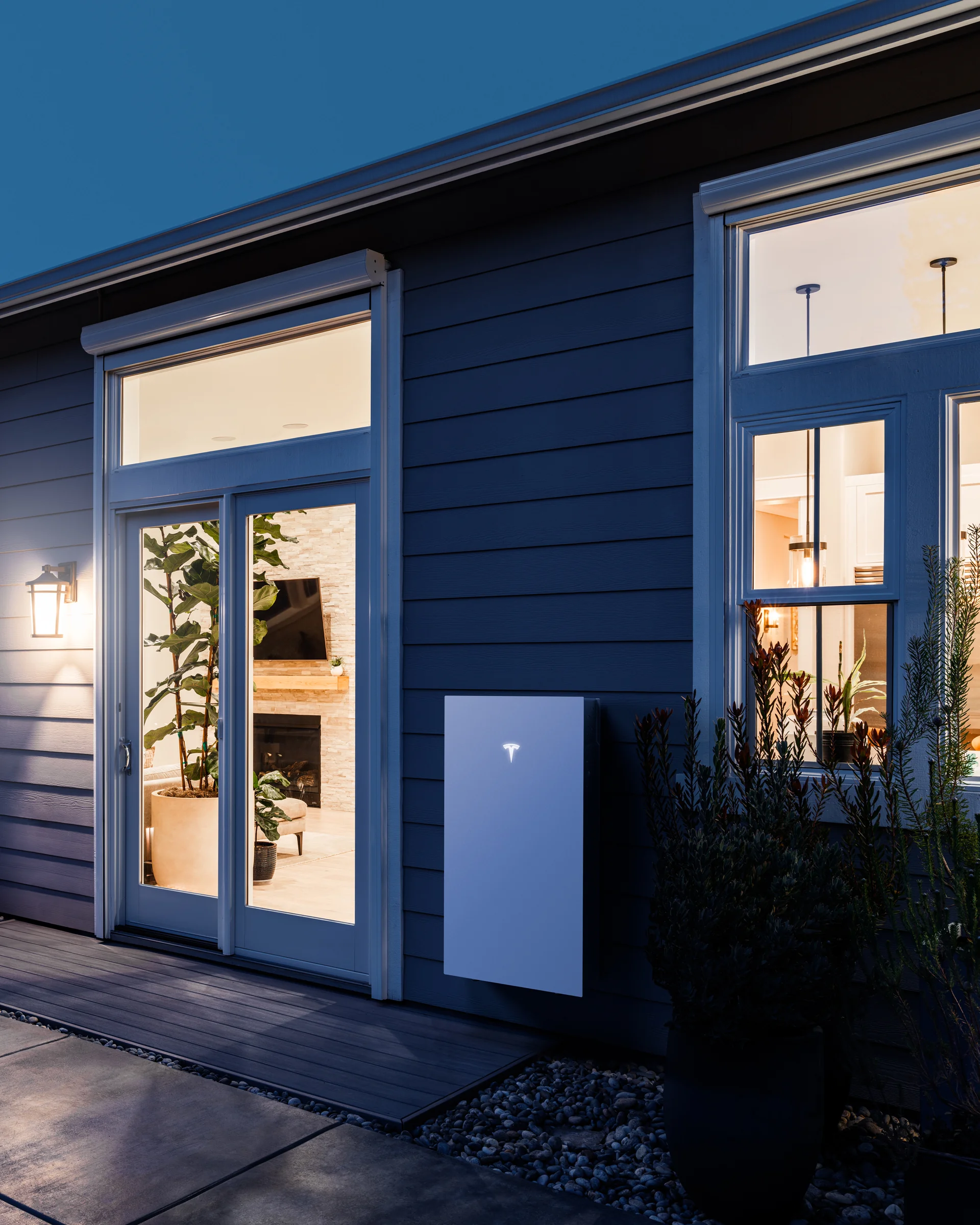 Tesla Powerwall 3 mounted on the exterior wall of a modern home at blue hour