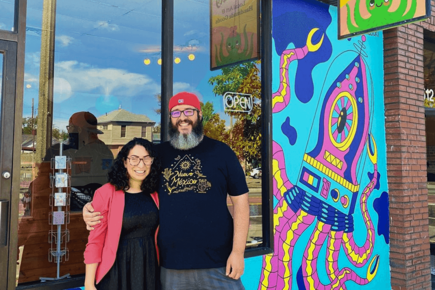 Store owners and guests gathered in front of custom Squidly Store mural