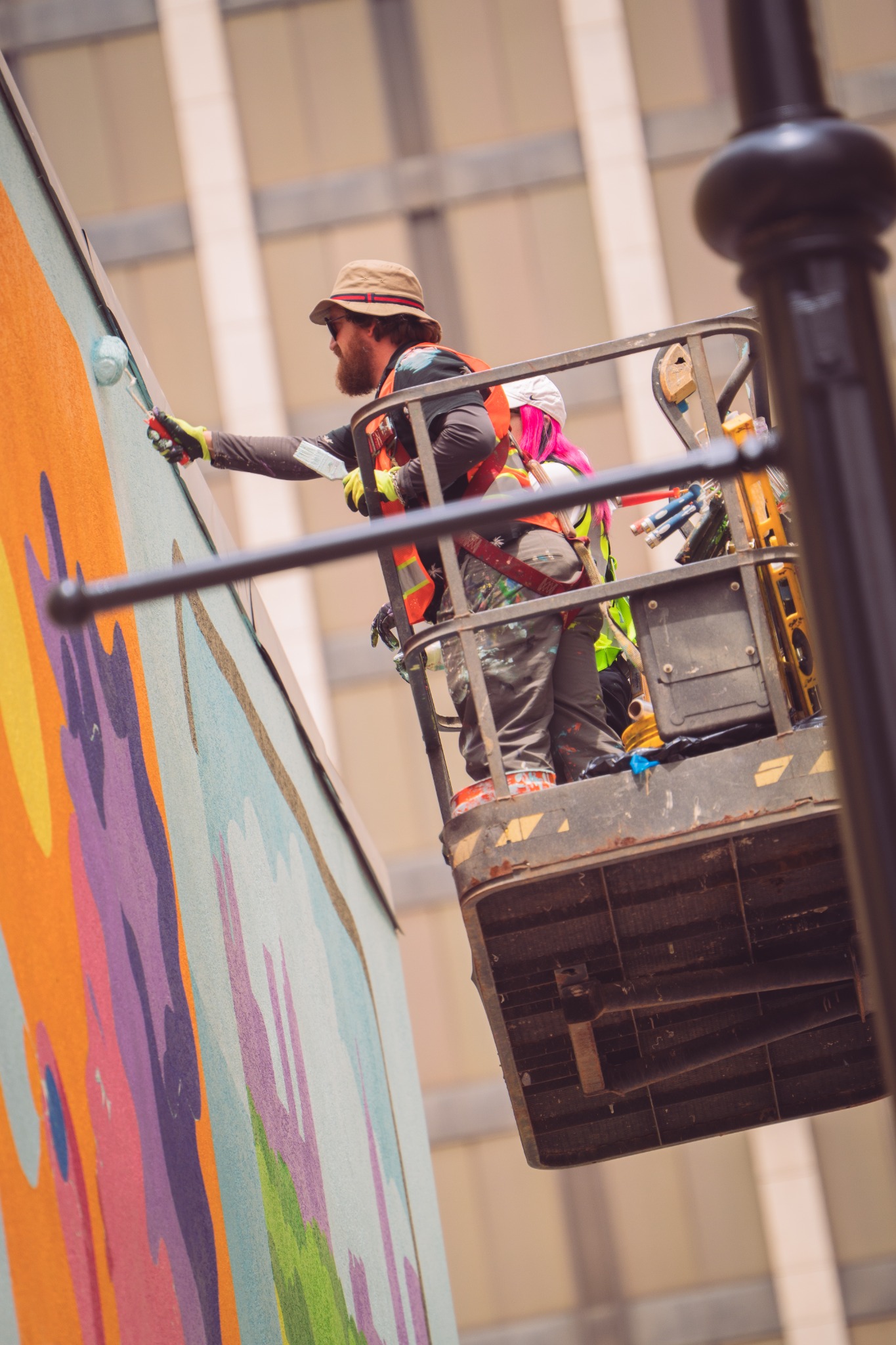 Artist working from a lift while painting a large-scale public mural by Brianna Gardocki.