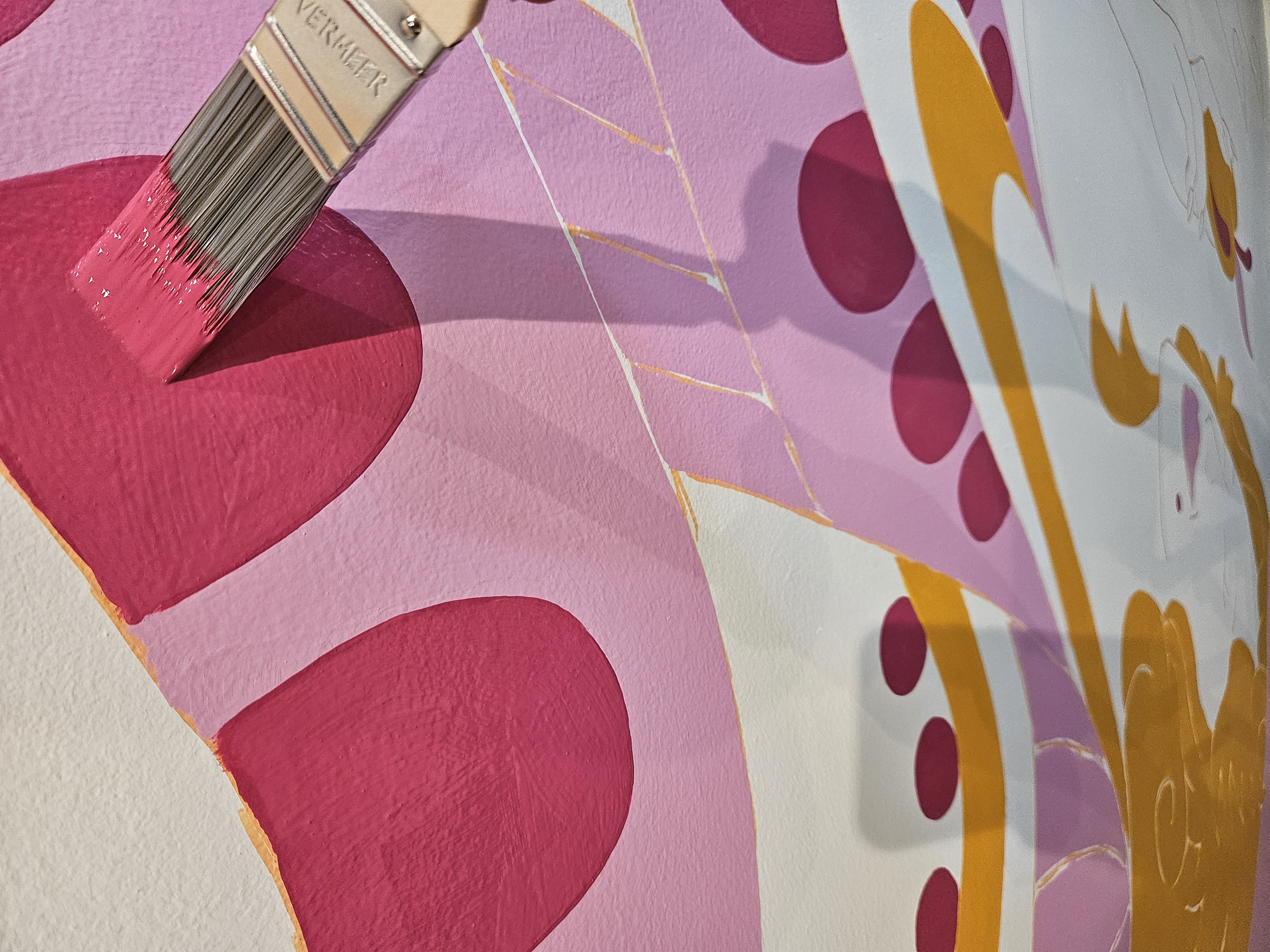 Brianna Gardocki painting heart shapes during installation of the Jolene Jolene of Hearts mural