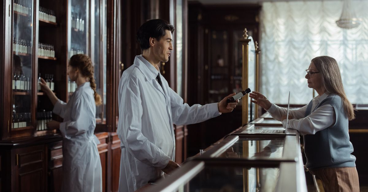 A pharmacist hands medication to a customer at a classic vintage pharmacy counter. — kaiser pharmacy