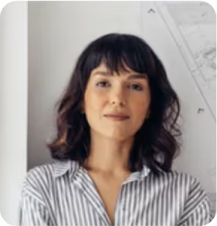 Professional woman in striped shirt poses confidently against white wall