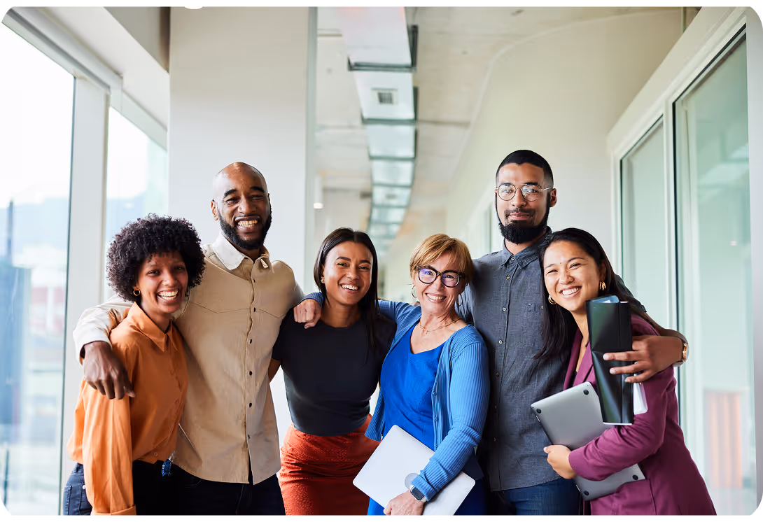 Diverse group of colleagues smiling together in bright office hallway