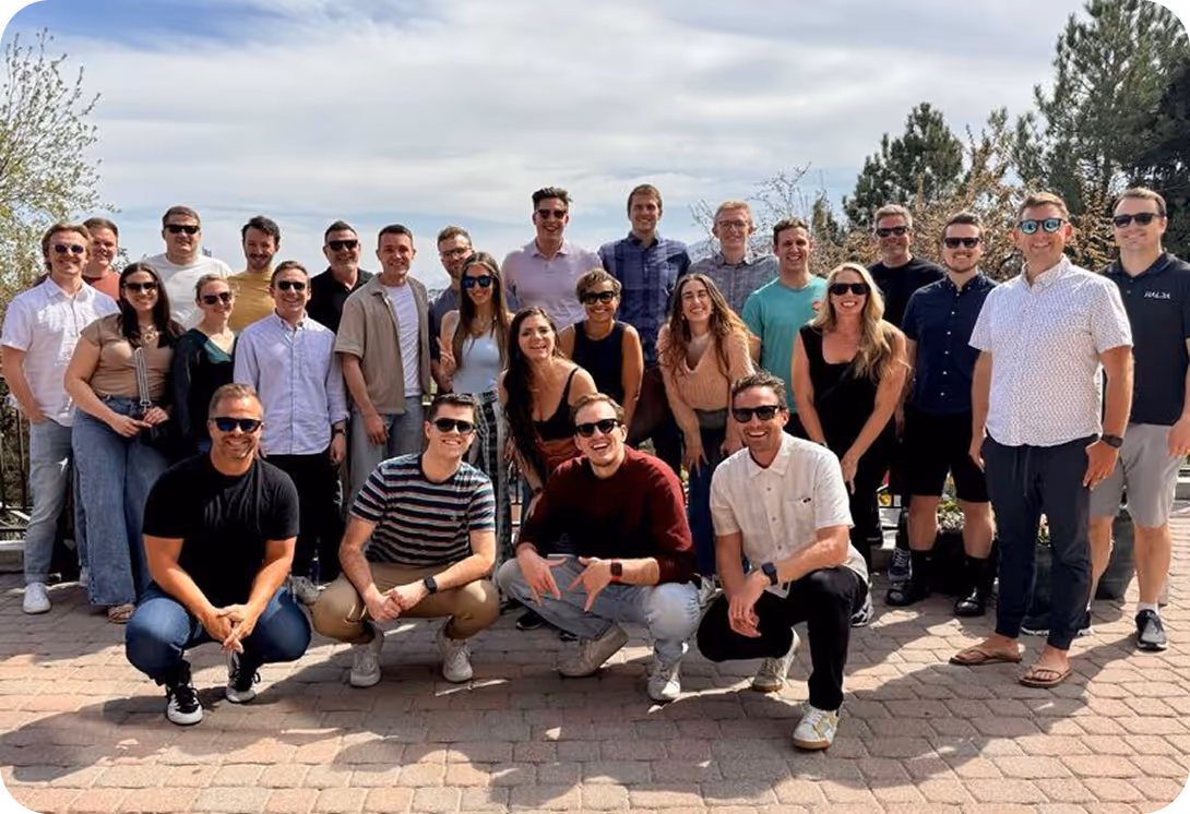 Large group photo of team outside on brick patio wearing sunglasses
