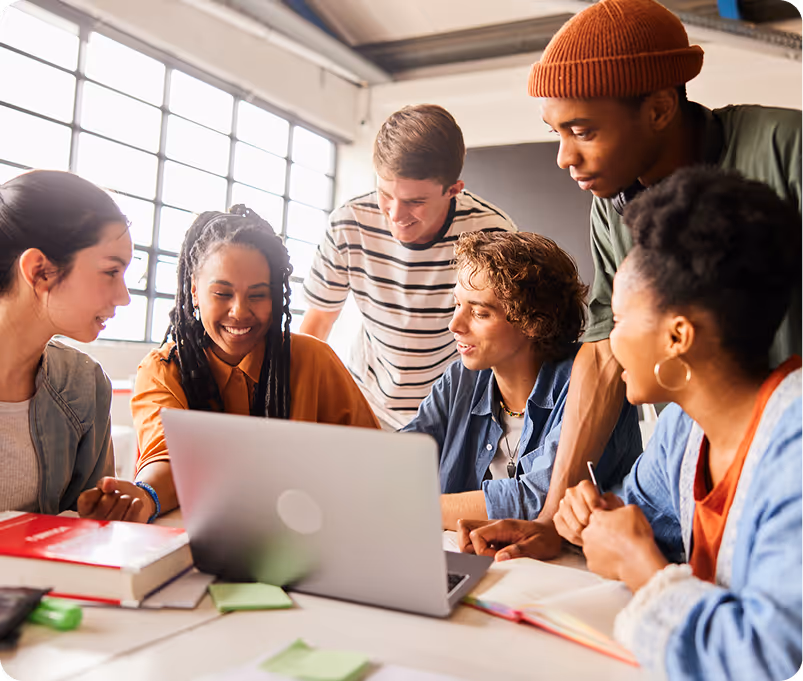 Four female students sitting on outdoor steps, three chatting while one in a green hoodie looks at her phone.