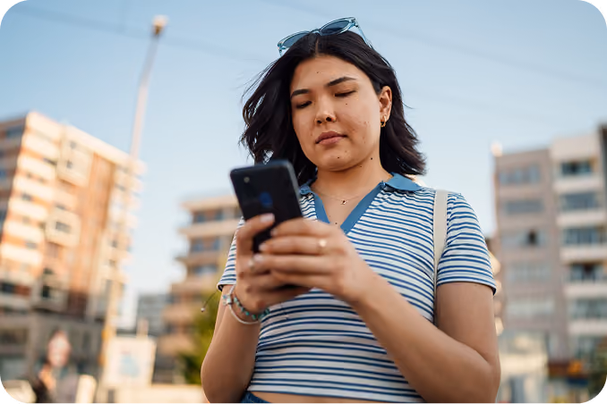 A prospective student checking her phone outdoors