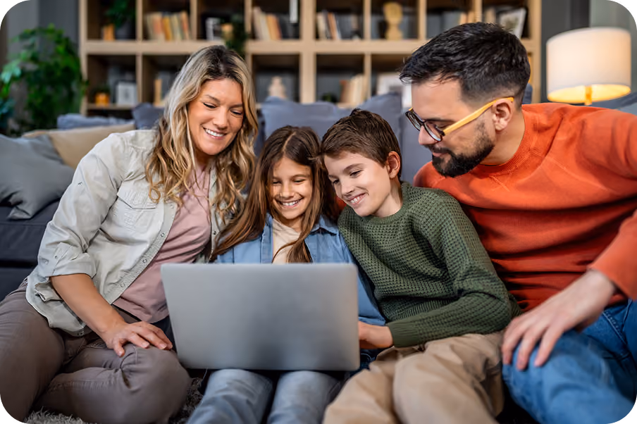 A family of four looking at a laptop together on the sofa