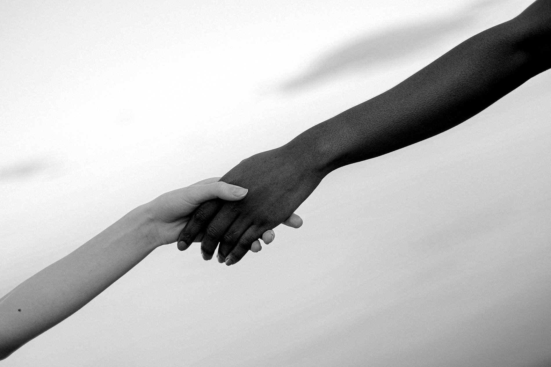 Two hands reaching out and clasping one another, photographed in black and white