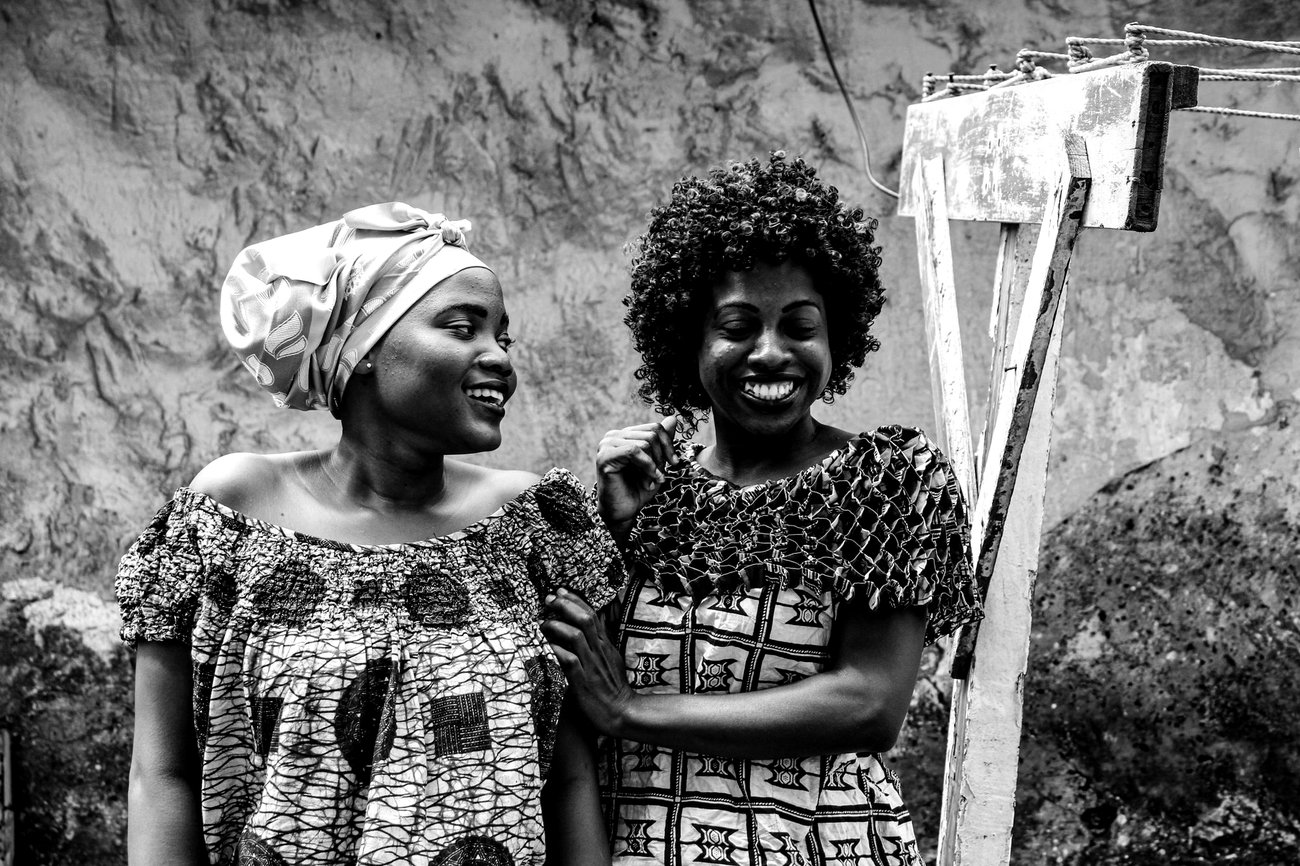 Two women laughing together outdoors, photographed in black and white