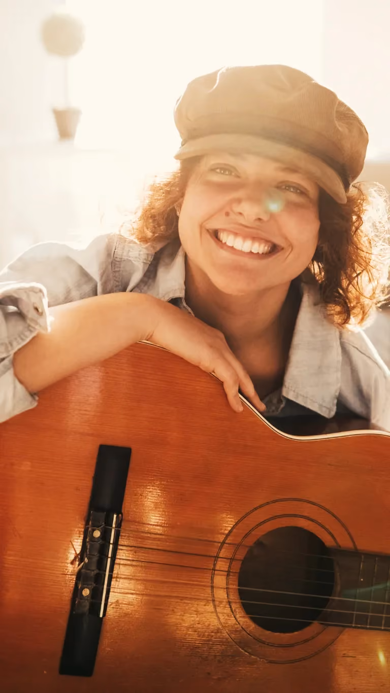 Frau lacht und hält eine Gitarre in der Hand