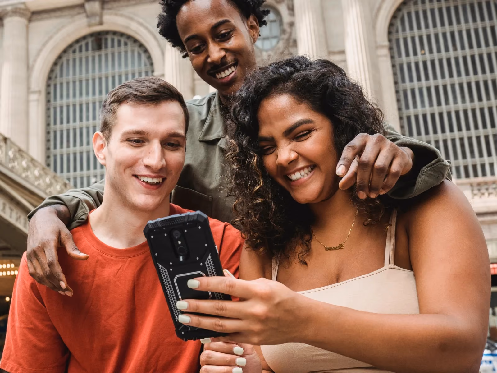 3 Freunde schauen aufs Handy und freuen sich