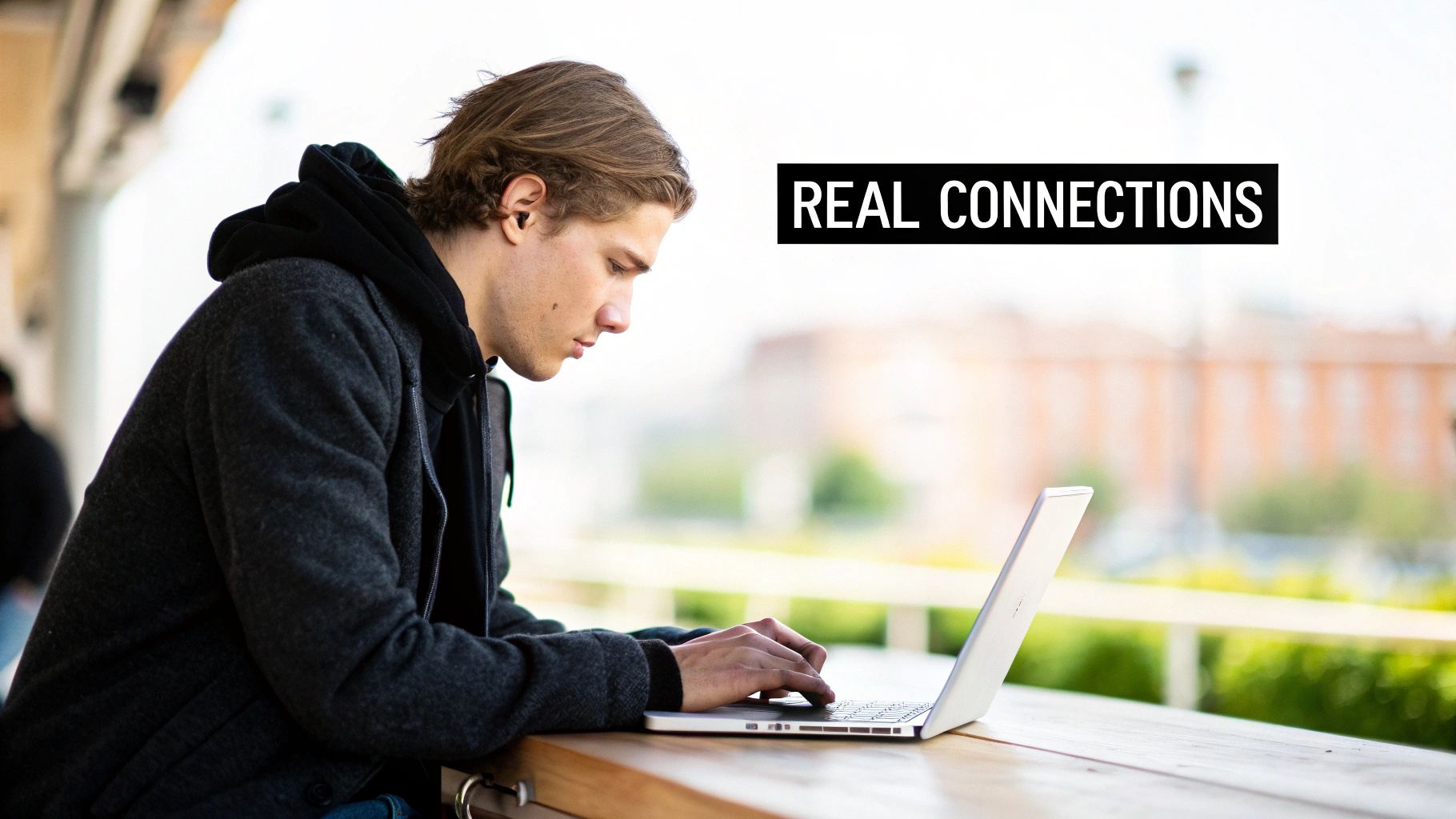 A young man with an earbud uses a laptop outdoors, working or connecting online.