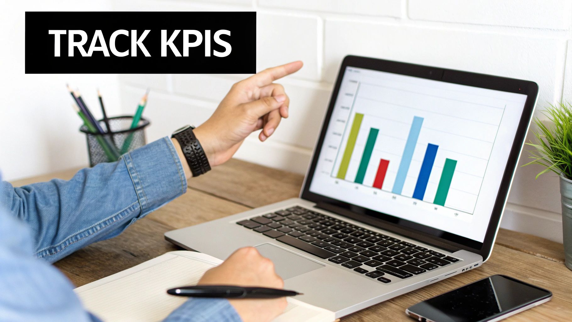 A person points at a laptop displaying a bar chart, with 'TRACK KPIS' text overlay.