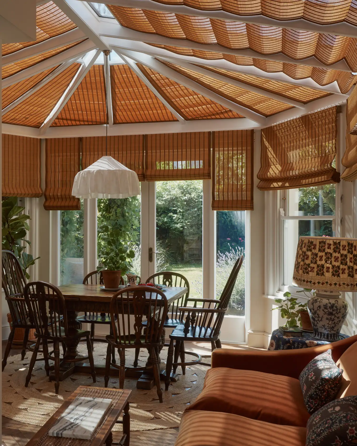The London garden room with bamboo roof blinds drawn above the dining table and seating