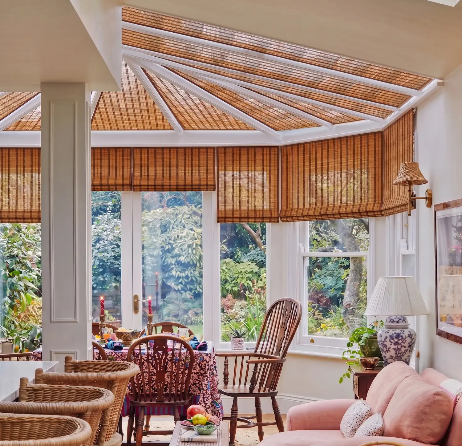 Garden room seating area beneath motorised bamboo roof blinds, looking out to the garden
