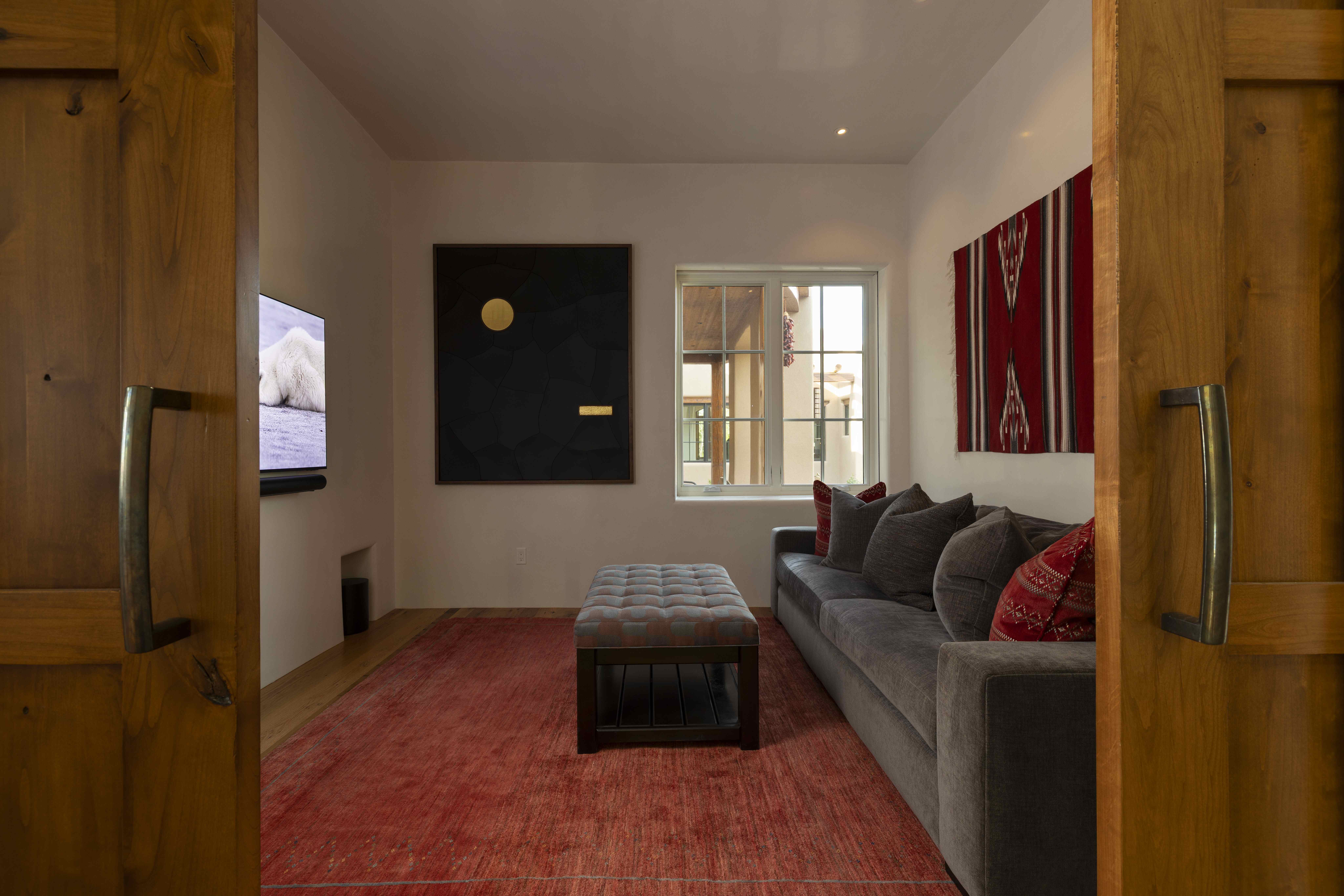 Media den with red rug, sofa and wall-mounted TV