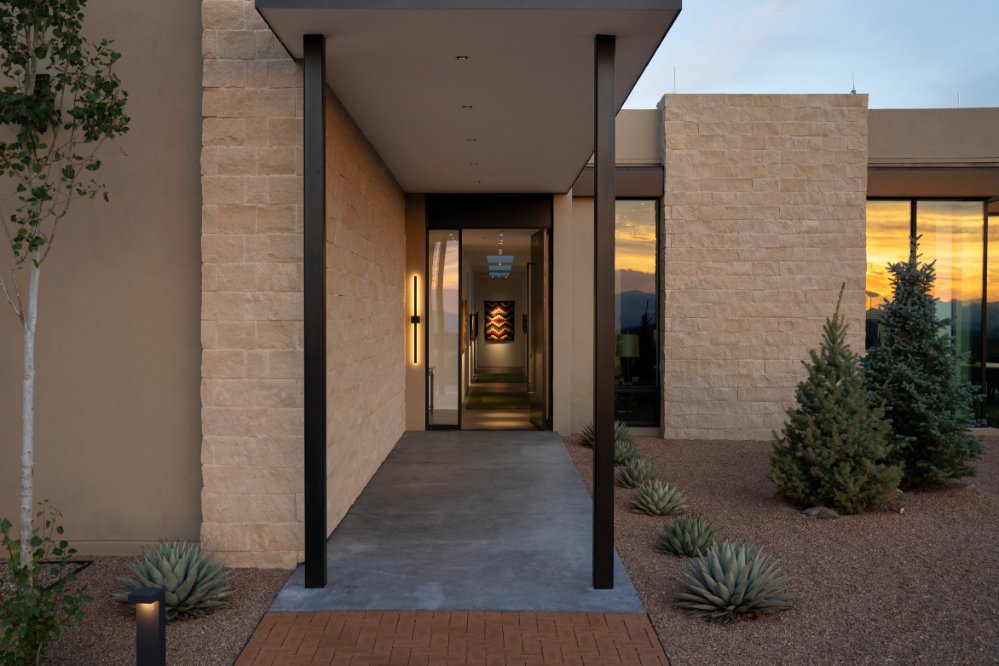 Lit entry walkway of a modern stone home at dusk