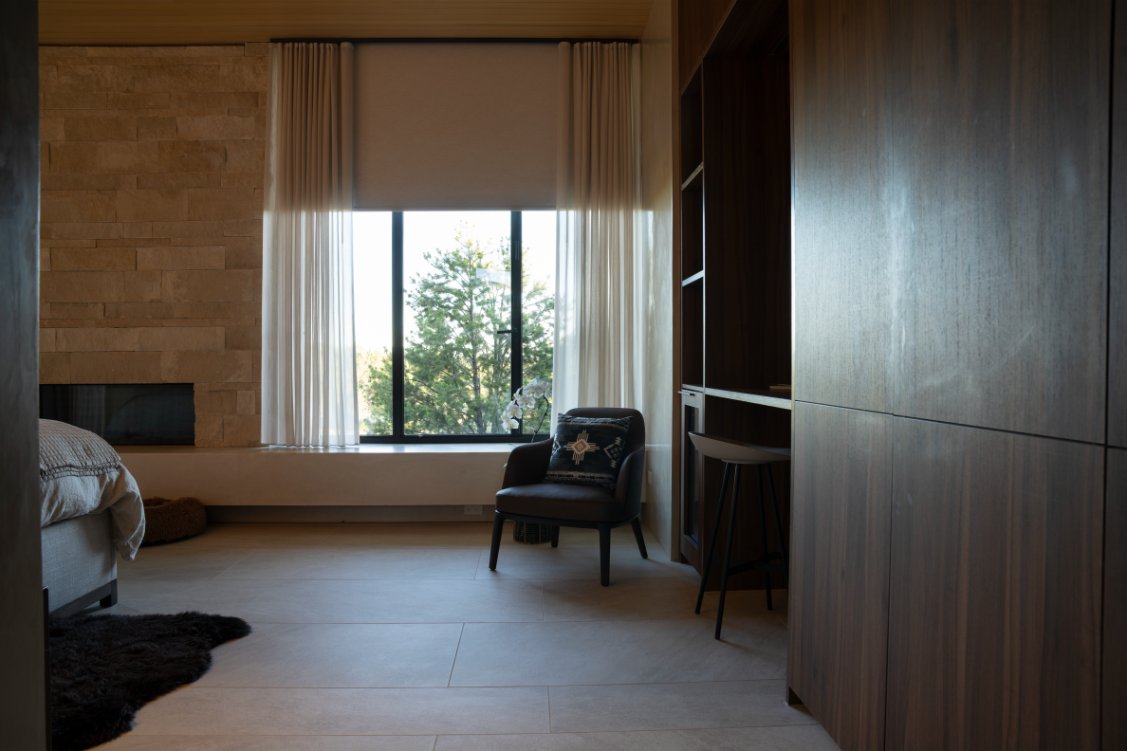 Primary bedroom sitting area with stone fireplace and motorized sheer shades