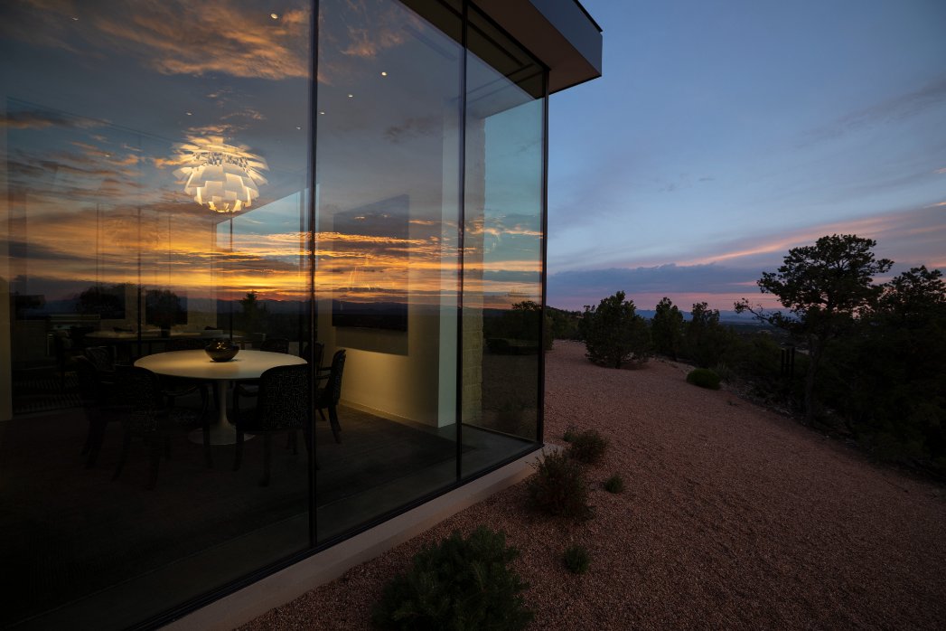 Glass-walled dining room glowing at sunset in a contemporary New Mexico home