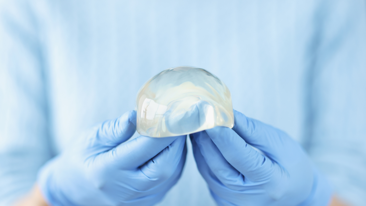 A nurse holding a breast implant ready for plastic surgery.
