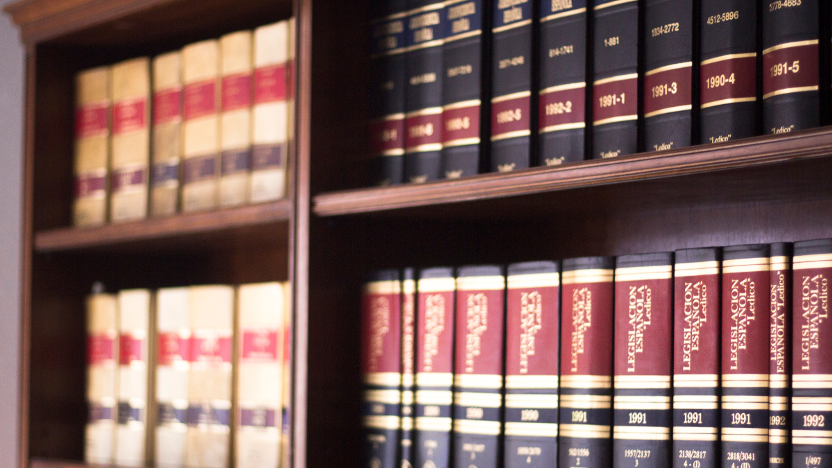 Bookshelf filled with legal books in leather bindings, many labeled 'Legislación Española' and dated from the 1990s.