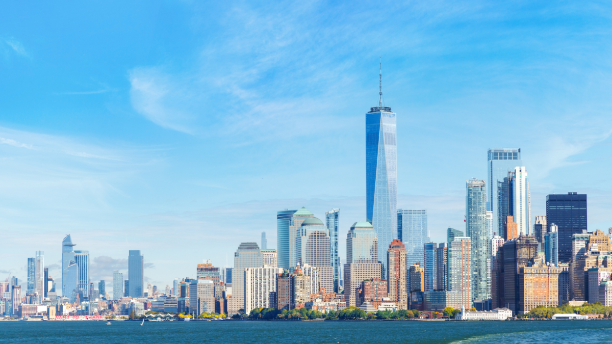 New York City skyline with One World Trade Center and other skyscrapers by a body of water.