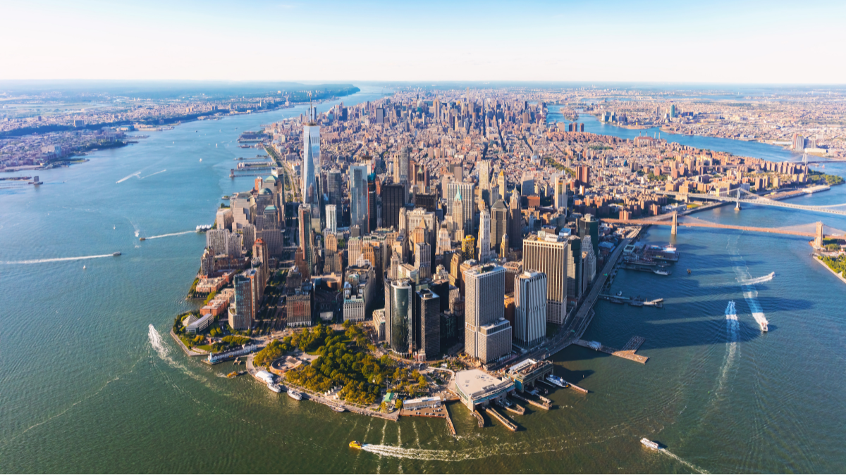 Aerial view of Manhattan, New York City, with skyscrapers, surrounding rivers, and several boats.