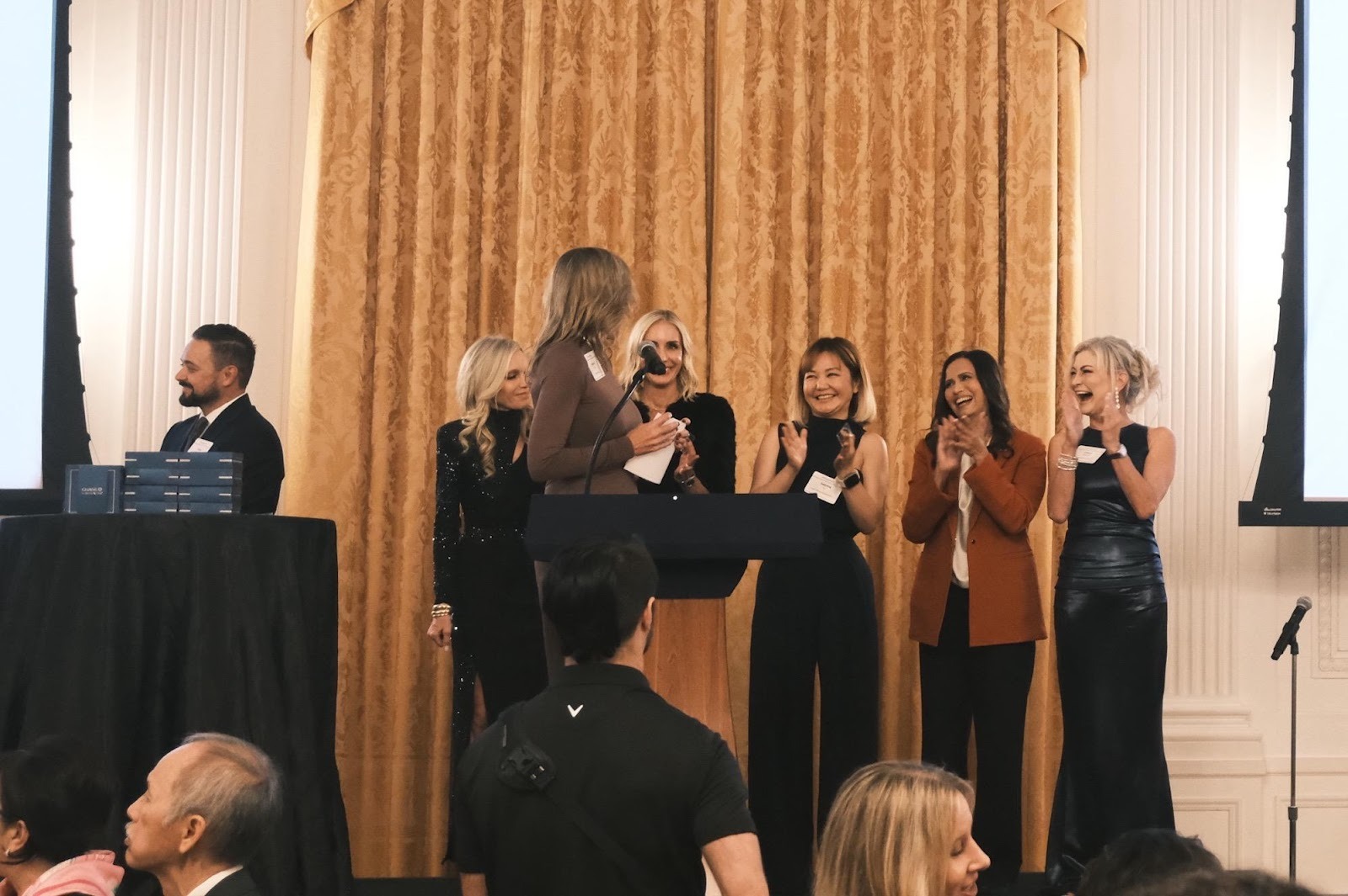 A group of women standing in front of a podiumAI-generated content may be incorrect.