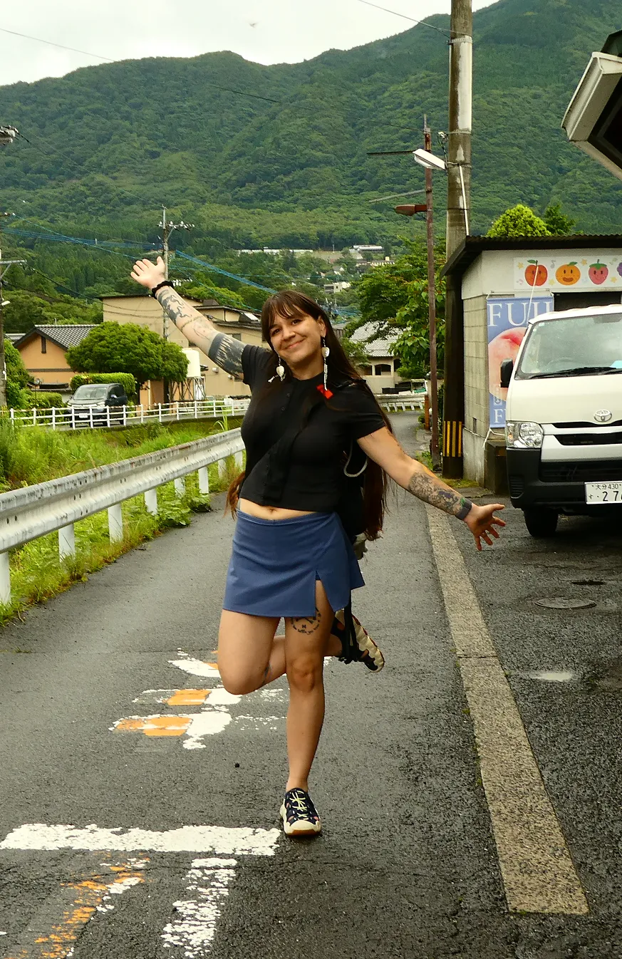Kae Sandt mid-kick with arms spread on a mountain road in Japan