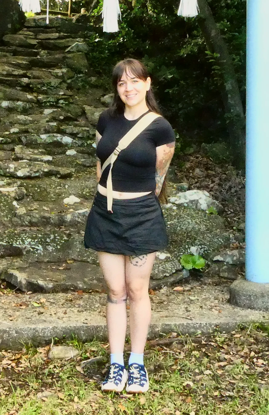 Kae Sandt standing on a stone path in front of a mossy stairway