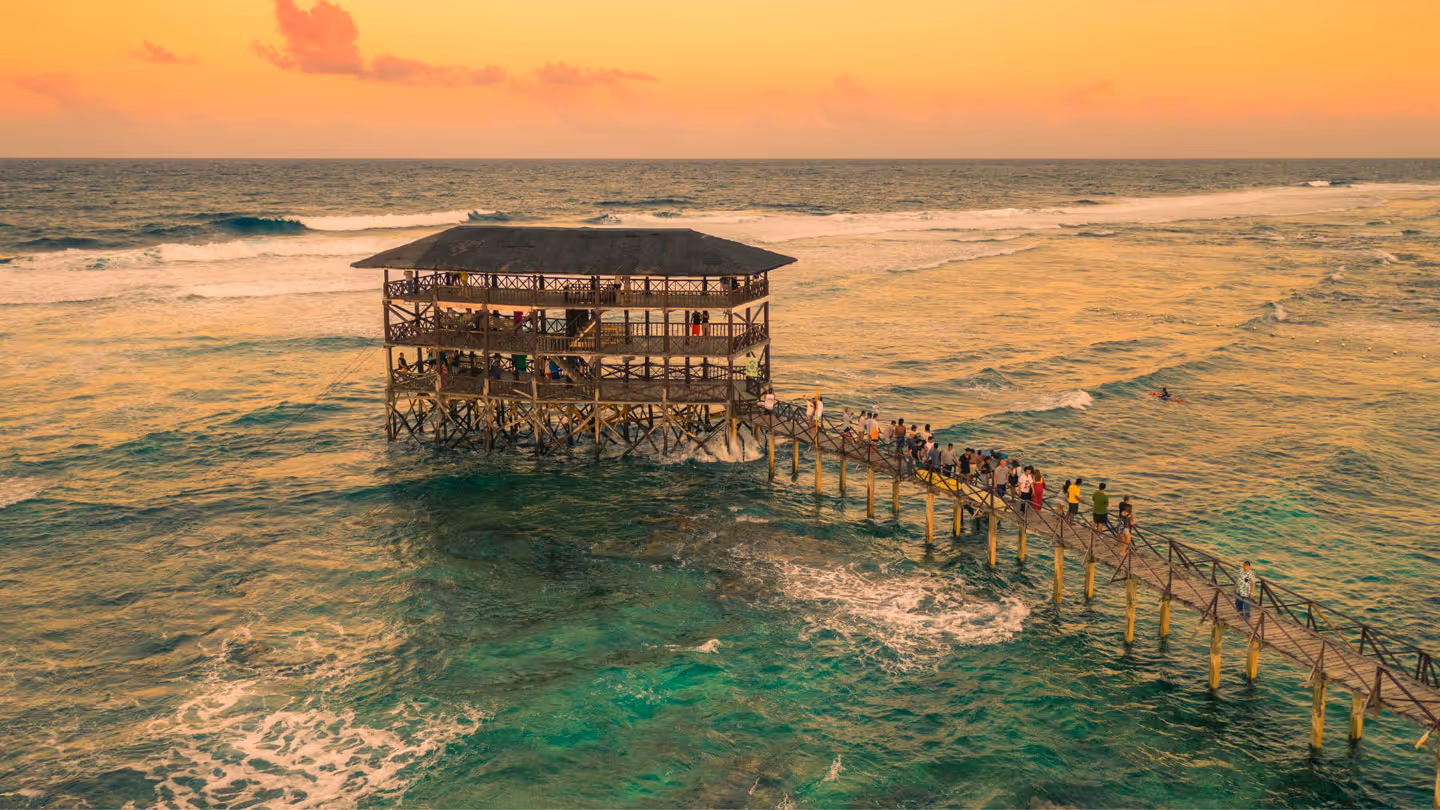 Sunset on most popular surfing area Cloud 9 at Siargao, Philippines. Aerial view raised wooden walkway for surfers to cross the reef of siargao island to cloud 9 surf break Mindanao.