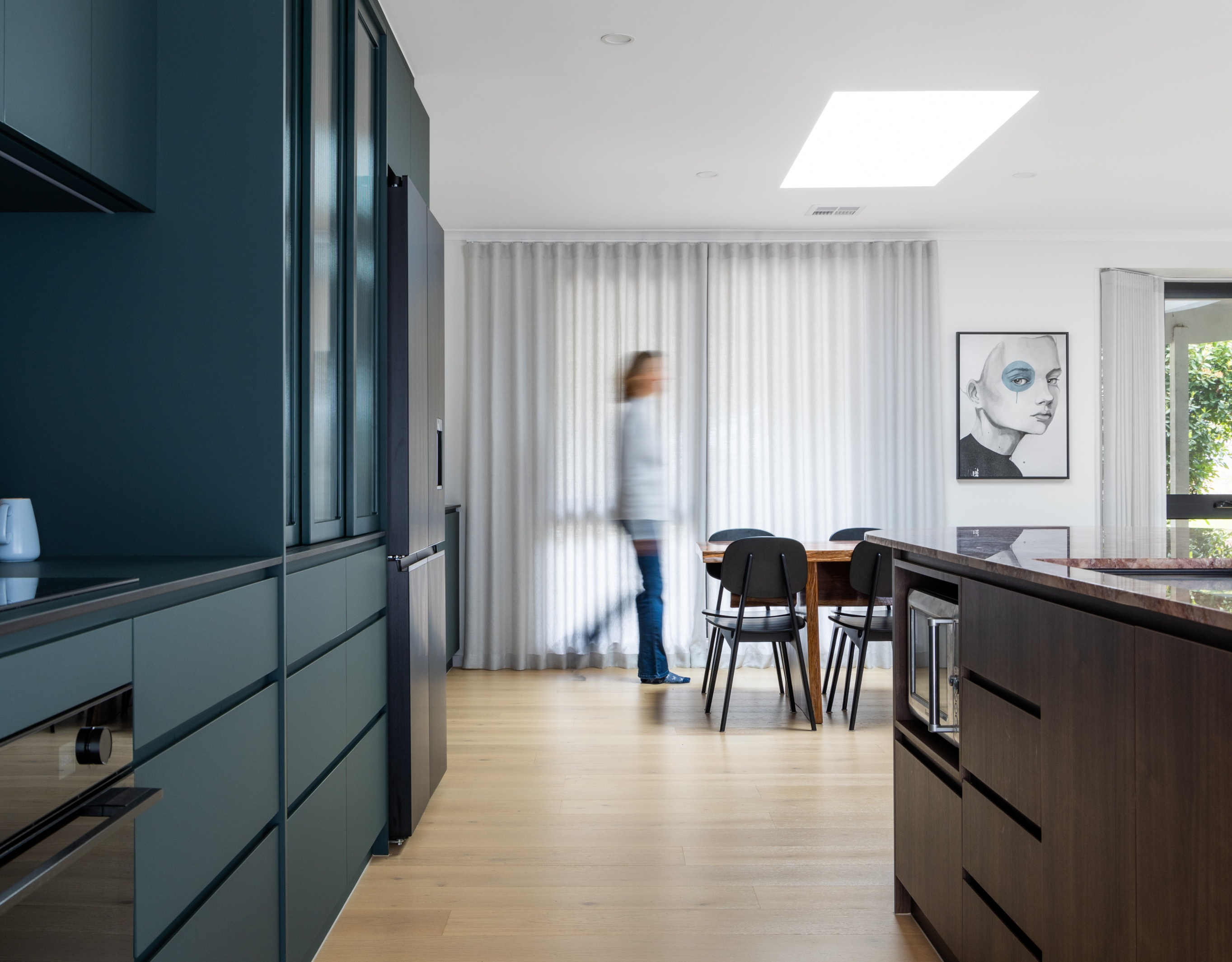 Modern kitchen with deep blue joinery looking towards open living area