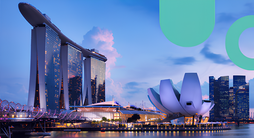 Evening skyline of Singapore featuring the Marina Bay Sands hotel with its curved rooftop architecture and the ArtScience Museum shaped like a lotus flower, with illuminated city buildings and a cloudy sky in the background.