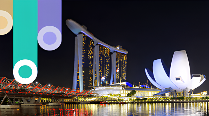 Night view of Marina Bay Sands hotel with three towers and a boat-shaped rooftop, lit up next to the illuminated lotus-shaped ArtScience Museum reflecting on the water with a dark sky background.