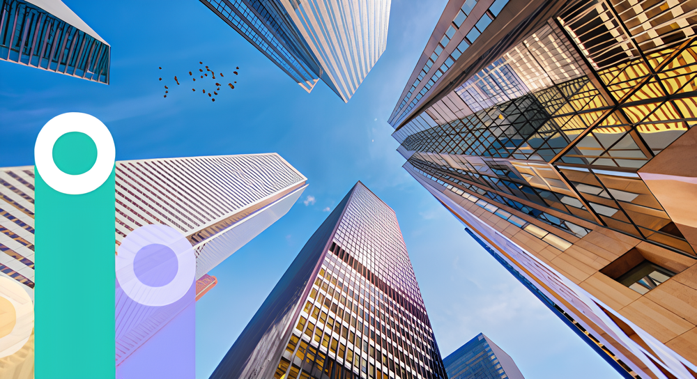 View looking up at tall skyscrapers with reflective glass windows against a blue sky with some birds flying, framed by colorful translucent graphic circles on the left.