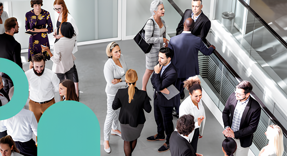 A diverse group of professionally dressed people engaged in conversation in a modern office space with glass railings.