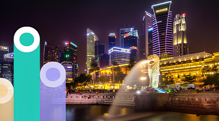 Night view of Singapore skyline with illuminated skyscrapers and the iconic Merlion statue in the foreground spouting water into the bay.