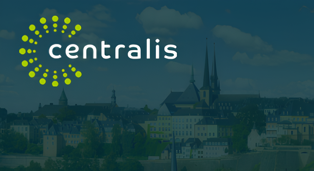 The Centralis logo featuring the brand name in white lowercase letters alongside a circular design of lime green dots on a blue-toned cityscape background with buildings and spires under a partly cloudy sky.