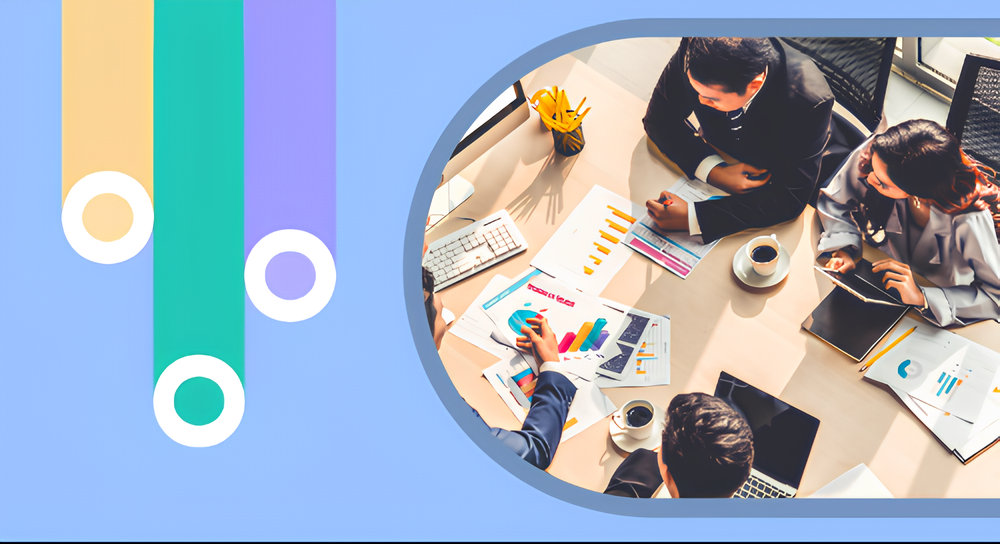 Overhead view of four business professionals sitting at a table with charts, graphs, laptops, tablets, and coffee cups, engaged in a discussion.