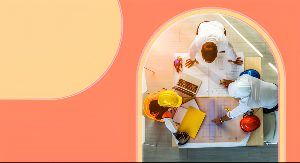 Overhead view of three architects or engineers, two with safety helmets, reviewing blueprints and documents spread on a table in a room with an arch-shaped window.
