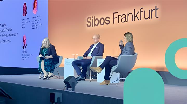 Three panelists seated on stage at the Sibos Frankfurt event, engaged in discussion with a large screen behind them displaying text and photos.