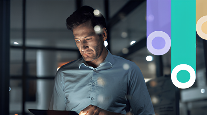 Man in a blue shirt looking focused while using a tablet in a dimly lit modern office with blurred lights and colorful vertical graphic bars overlay.