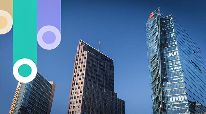 Two modern skyscrapers under a clear blue sky, one rectangular with many windows and one curved with a red logo at the top; decorated with vertical colorful graphics with circles on the left side.