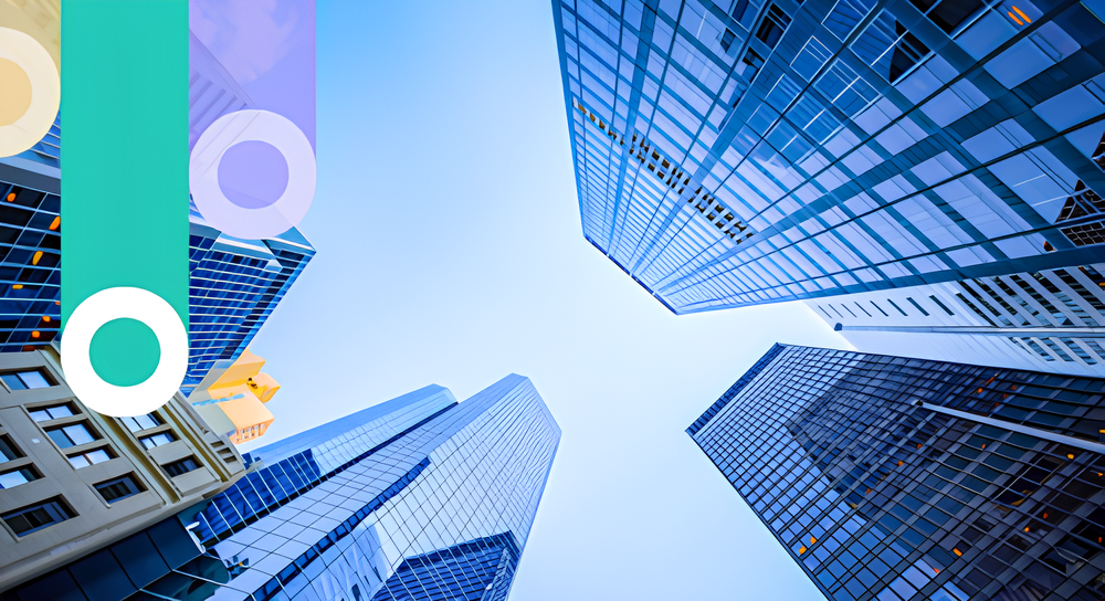 View looking up at tall modern glass skyscrapers against a clear blue sky in an urban setting.
