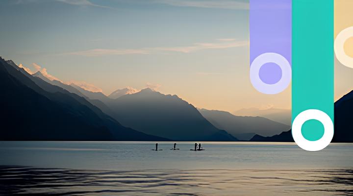 Calm lake at sunset with silhouetted mountains in the background and four people paddleboarding on the water.