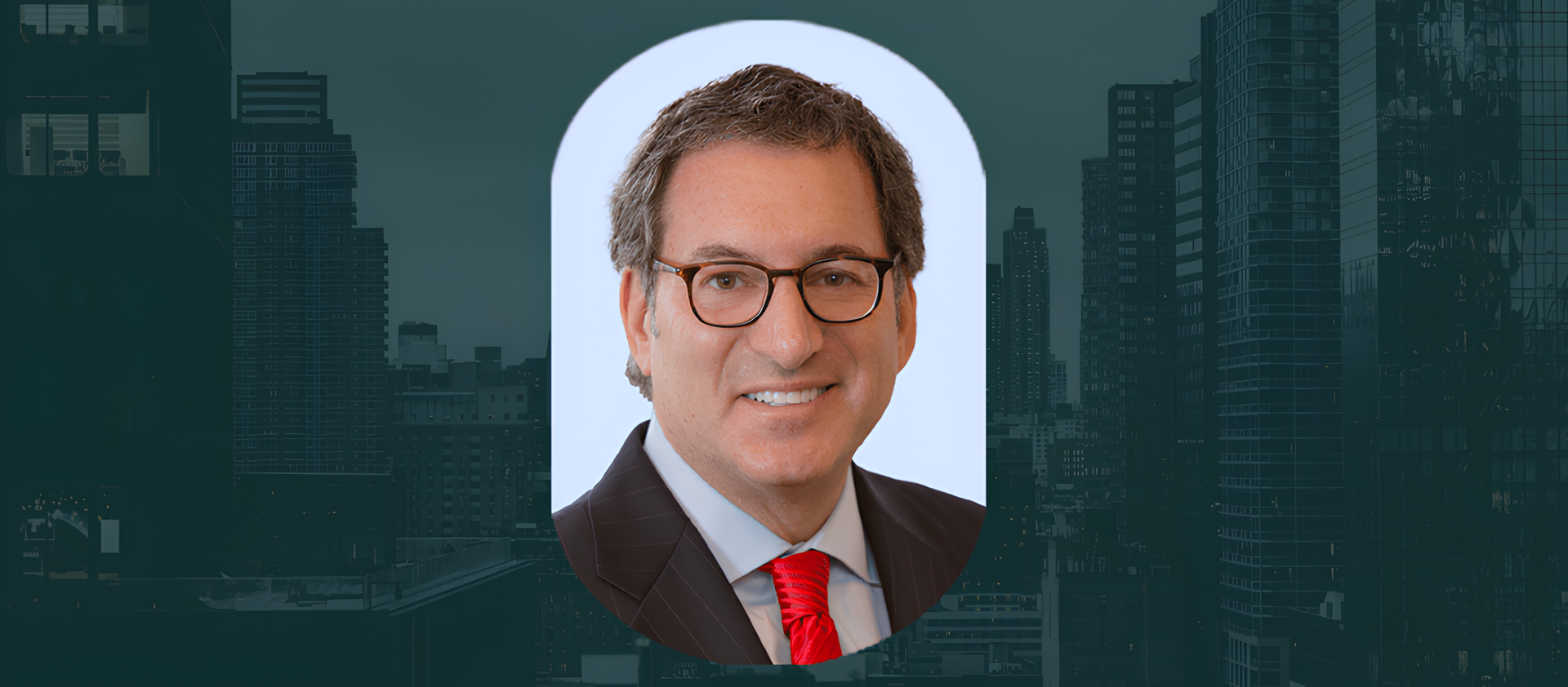 Smiling middle-aged man with brown hair and glasses, wearing a dark pinstripe suit, light blue shirt, and bright red tie, set against a light grey background with a dark cityscape behind.