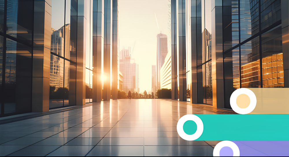 Sunset view down a reflective tiled walkway flanked by tall glass office buildings with city skyline in the background.