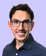 Smiling man with short dark hair, wearing glasses and a dark collared shirt, against a light purple background.